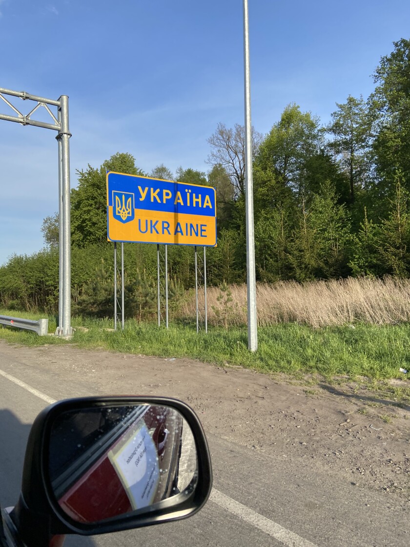 A blue and yellow road sign says Ukraine