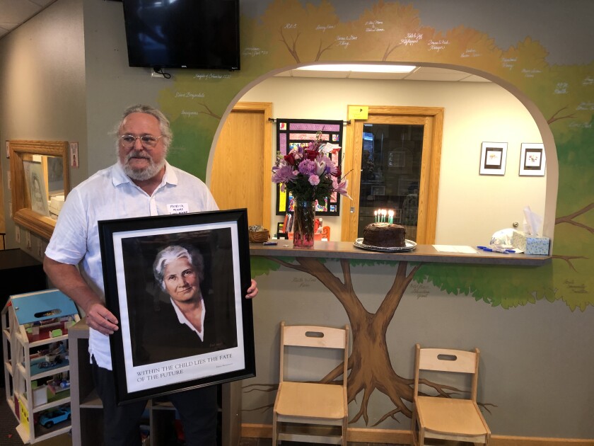 Patrick Moore, a member of the board of directors of the Wildwood Montessori School in Montevideo, holds a portrait of the late Maria Montessori as the school hosted a celebration on her birth date to mark the local school's success transition to a center-based child facility. Supporters raised $120,000 to support the school, one a very few rural Montessori Schools.
