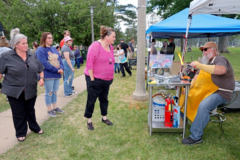 People watch as Mark Cross does glass lampwork at his booth while at Arts in the Park on Sunday, June 26, 2022, at Gregory Park in Brainerd.