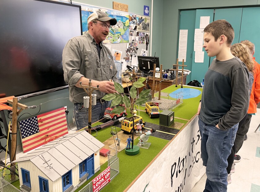 A lineman talks with a student at their presentation table.