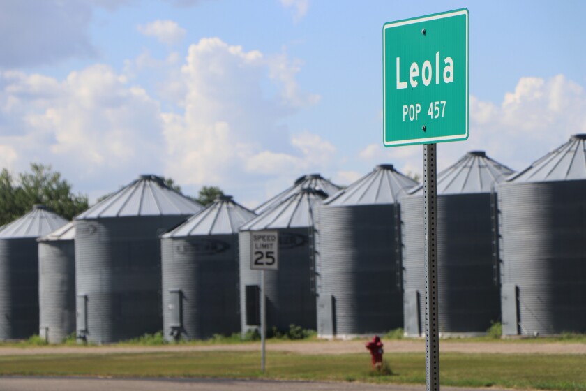A green highway sign, with the words, Leola, Population 457, is flanked by a row of steel grain bins at the south end of the South Dakota town.