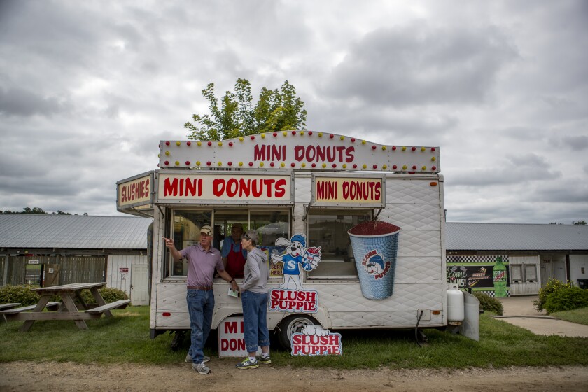 Fair-goers chat at a mini donut stand at the Kandiyohi County Fair on Saturday, August 13, 2022
