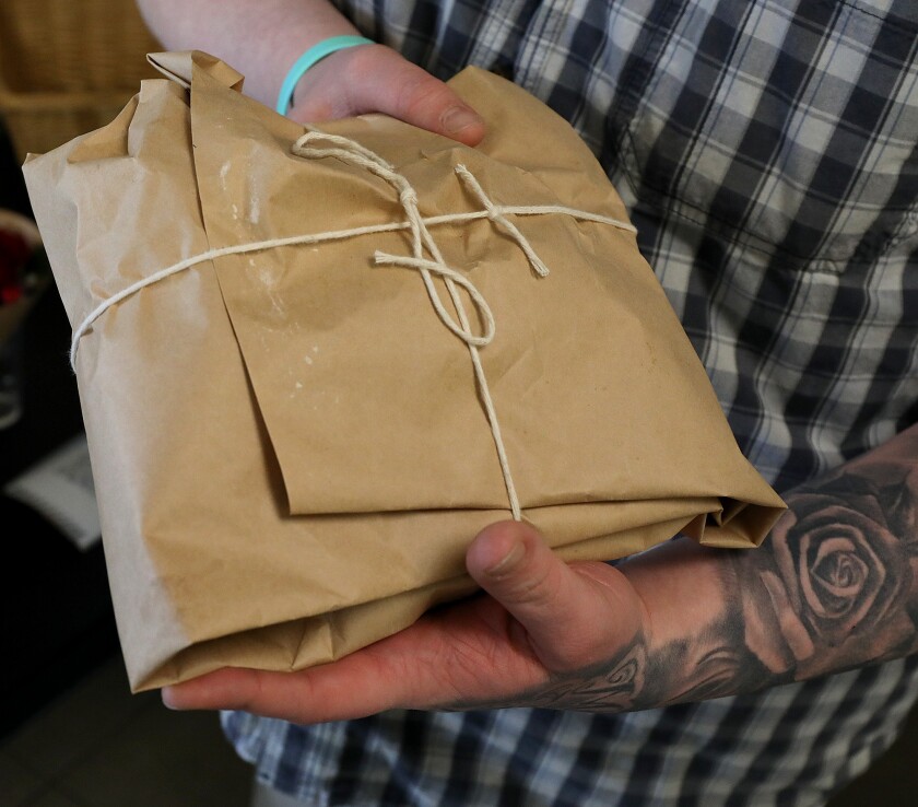 Chef Paul Lukens holds onto bread tied up in butcher paper