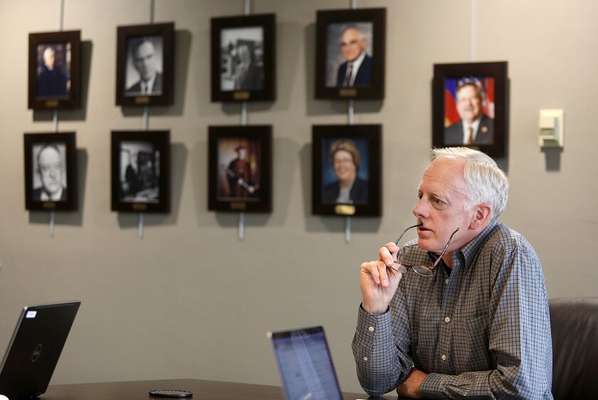 New Minnesota Duluth Chancellor David McMillian ponders a question while sitting under photographs of former chancellors in a conference room on the fifth floor of the Darland Administration Building on the UMD campus