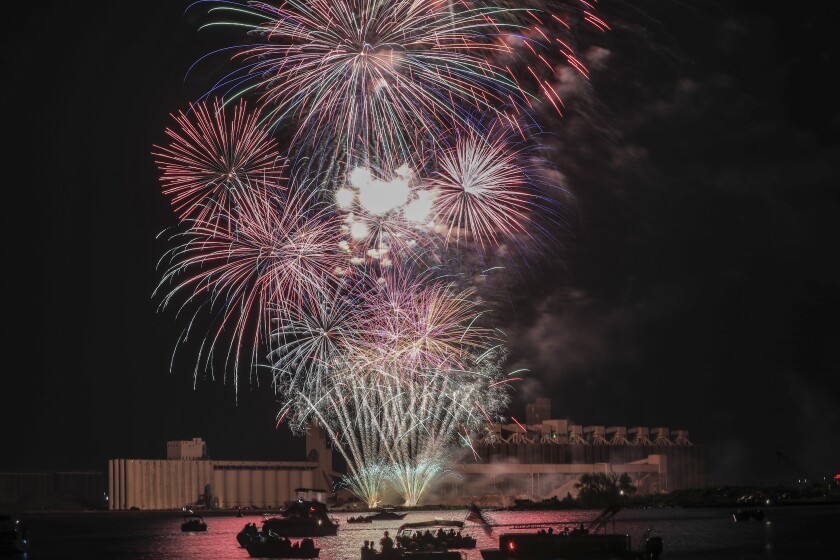 Fireworks fill night sky with moon over harbor