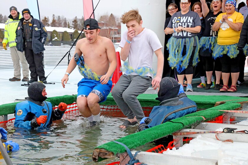 People jump into the water during the Polar Plunge event on Pelican Lake.