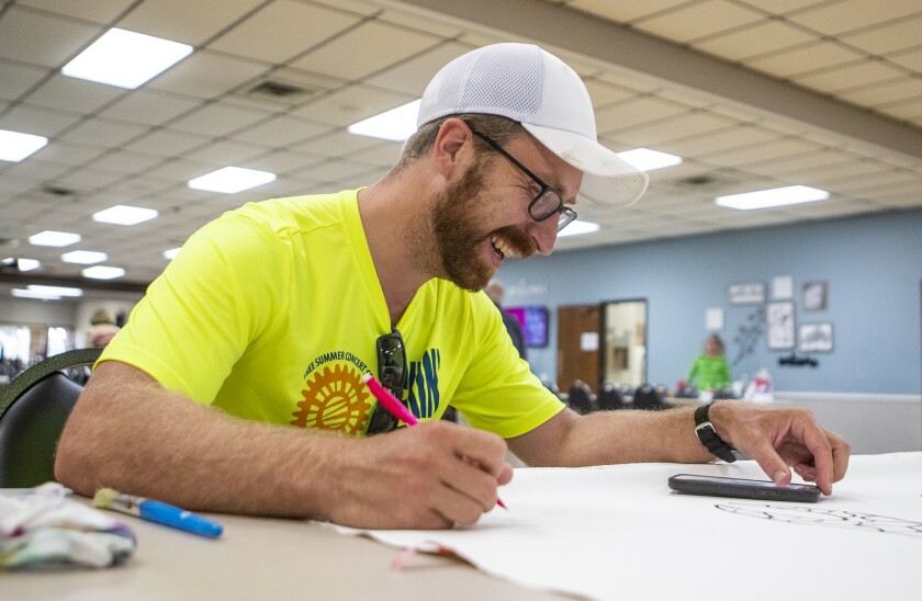 Chris Radel smiles while drawing on the Willmar Little Art Gallery mural at the Willmar Community Center on Tuesday, July 26, 2022.