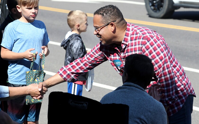 Minnesota Attorney General Keith Ellison, right, shakes hands with the crowd as he walks along Cloquet Avenue during the Labor Day parade in Cloquet