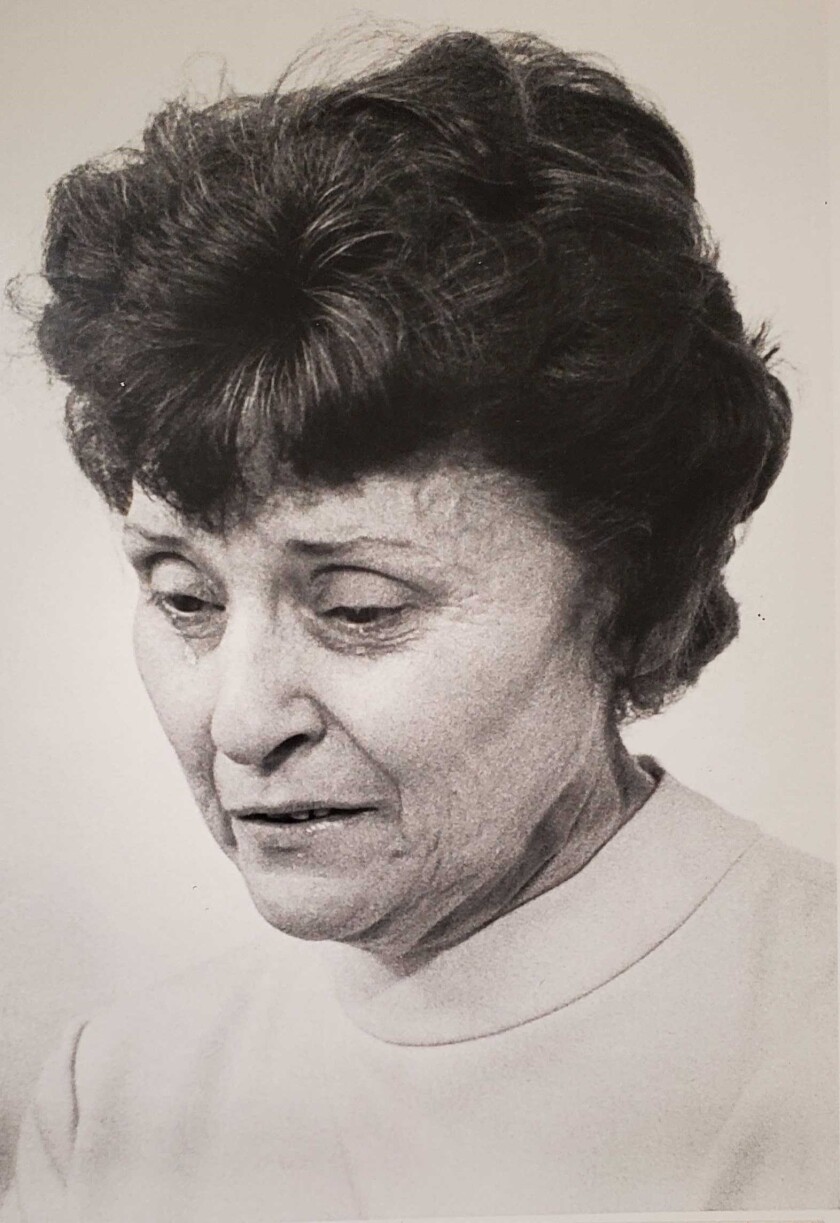 A black-and-white newsprint photo of a woman with short, curled hair and tears falling from her eyes.