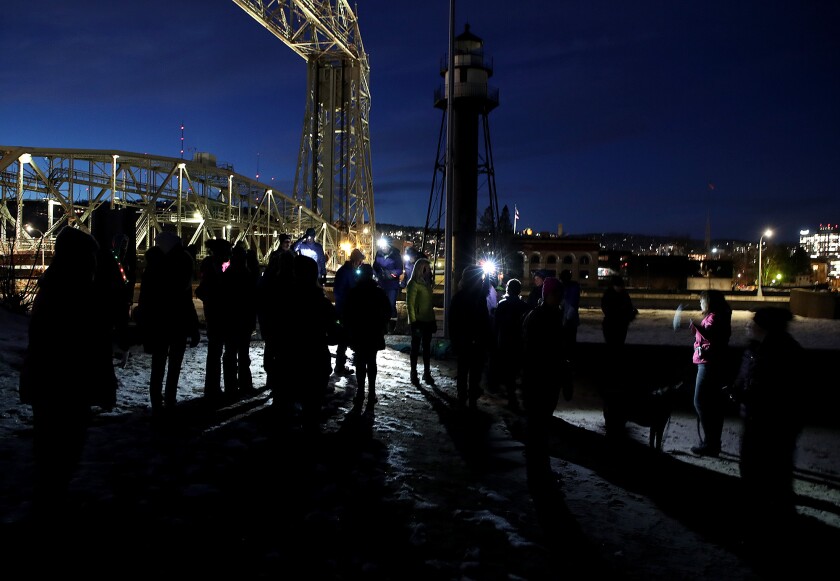 A group of people gather near the base of the bridge. Some of folks are wearing headlamps.