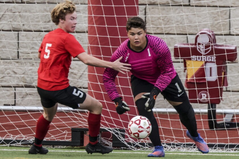 High school boys soccer players in red uniforms playing players in white uniforms outdoors