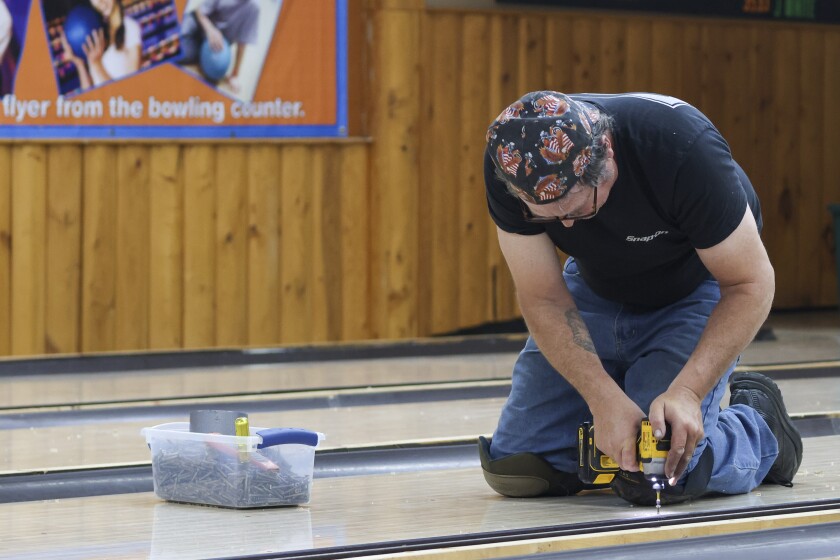 Workers using power tools to disassemble bowling lanes and equipment