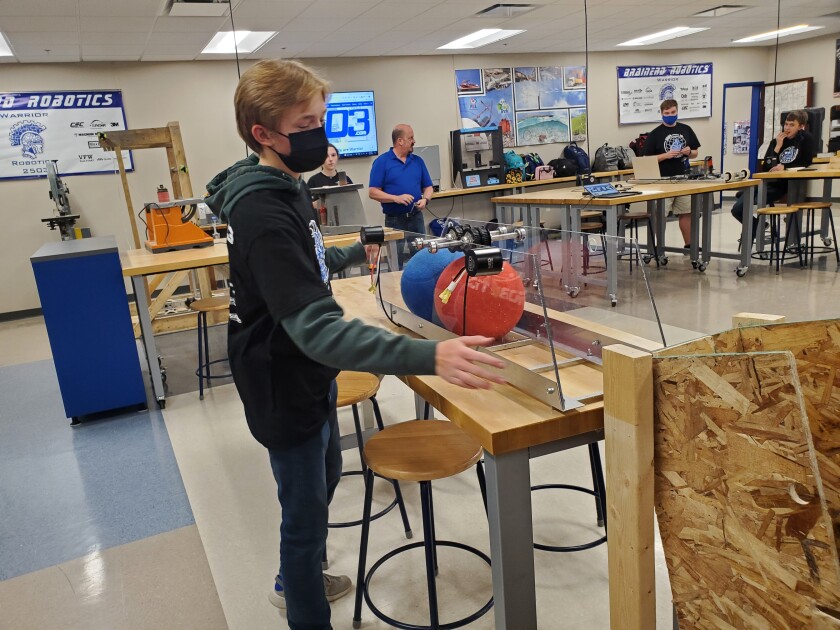 High school student stands with robot
