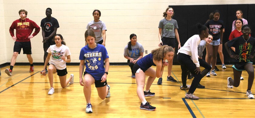 Worthington Trojans (center left) Karissa Bickett and Jenna Hoffman lead the team in stretching exercise during indoor practice due to cold wet weather Wednesday afternoon.