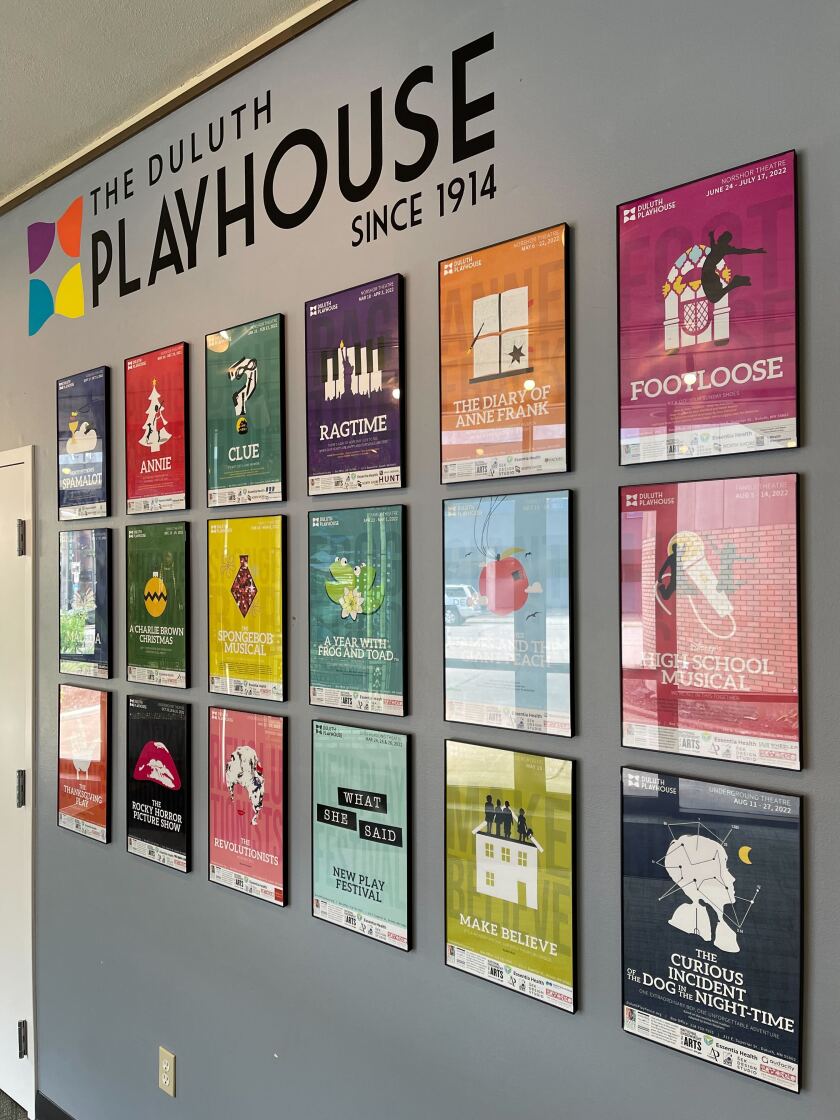 Theatrical promotion posters line a wall underneath the Duluth Playhouse logo