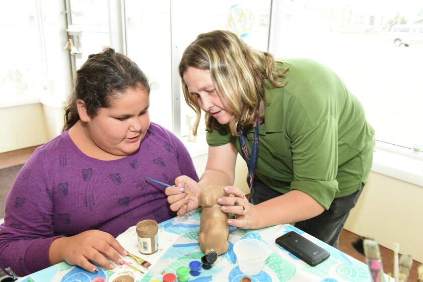 Jada Bath-Thurstin (left) learns how to paint from It's All About Ceramics owner Dawn Pierce at their store on Washington Street. (Brainerd Dispatch/ Steve Kohls)