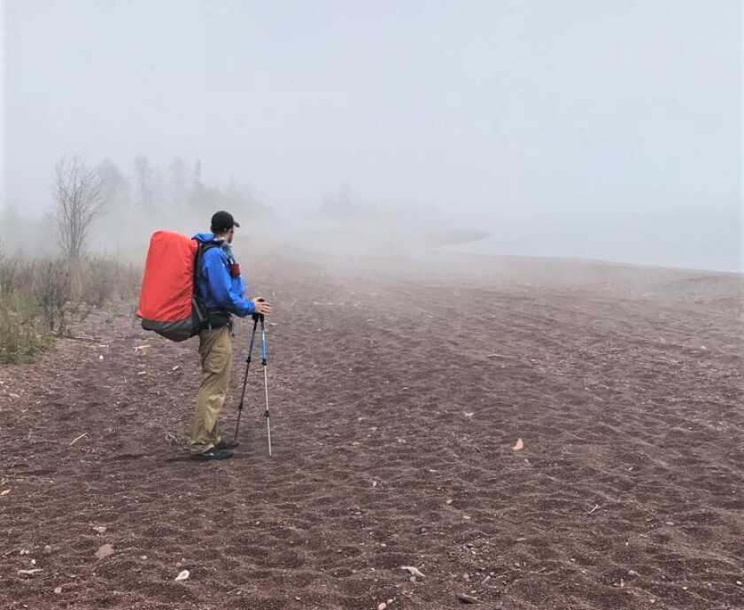 Adam Wallenta pauses to watch fog roll over Lake Superior along the Superior Hiking Trail's lakewalk section — a 1.5-mile section of trail by the lake north of Grand Marais. (Jimmy Lovrien/ jlovrien@duluthnews.com)