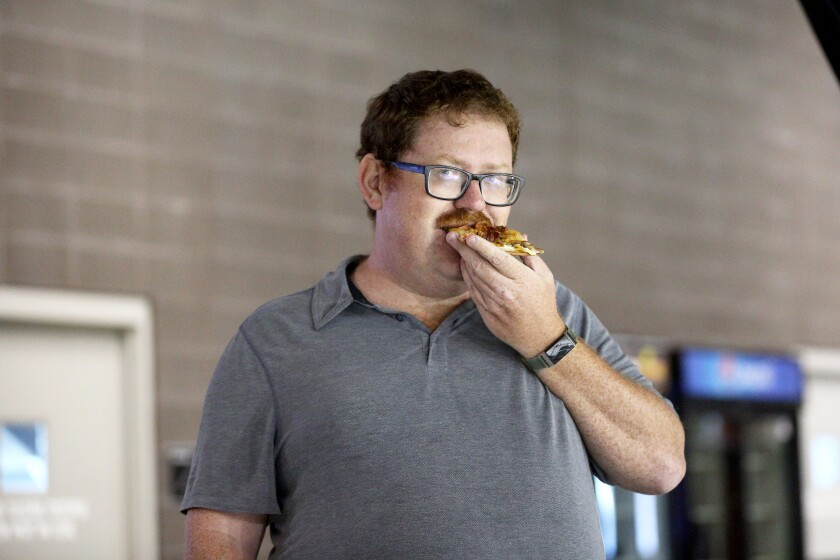 A man samples pizza during a concession food event.