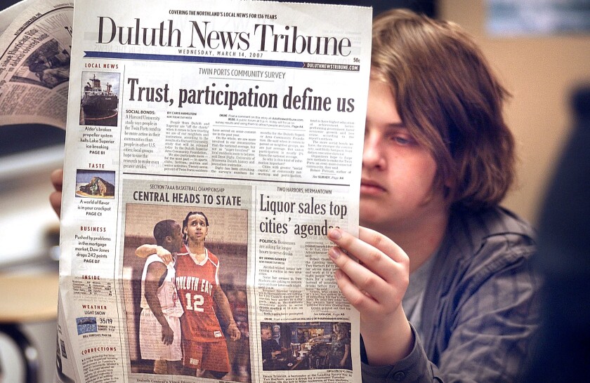 Light-skinned high school student reads Duluth News Tribune. Headline reads, "Trust, participation define us."