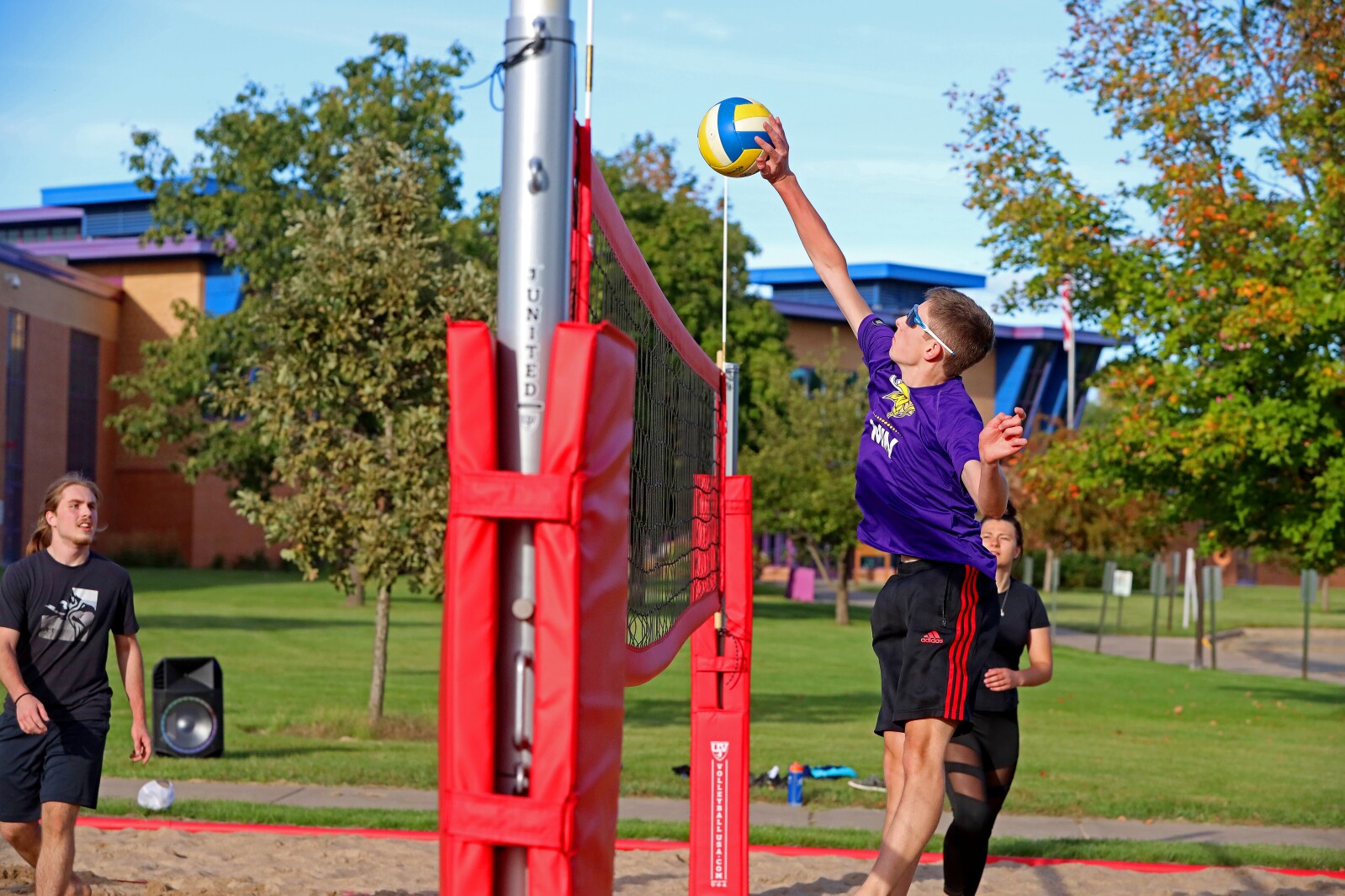 Volleyball players compete outside on the sand volleyball courts at CLC.