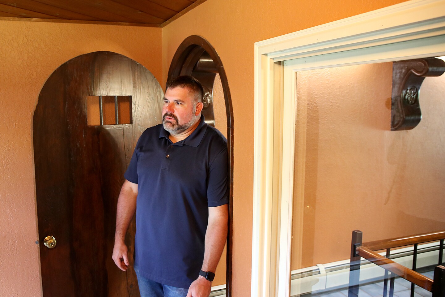 Man leans in curved doorway.