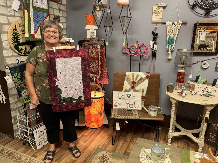 Rose Greninger holds up something she made and plans to sell while standing inside All Through the House, a crafters’ cooperative on Minnesota Avenue North in Aitkin.