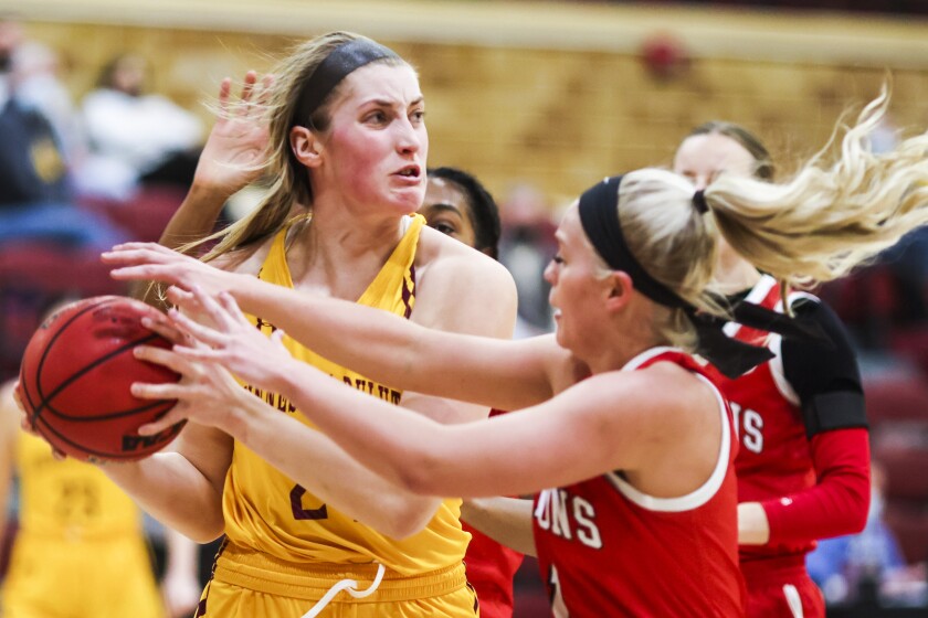 Women's college basketball players in yellow uniforms play against a team in red uniforms in a college gymnasium