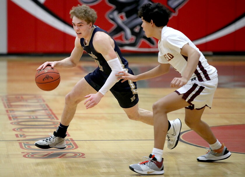 Player in blue dribbles past player in white.