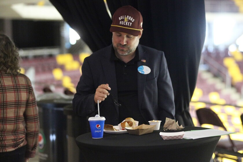 A man sampling concession food items while standing by a table.