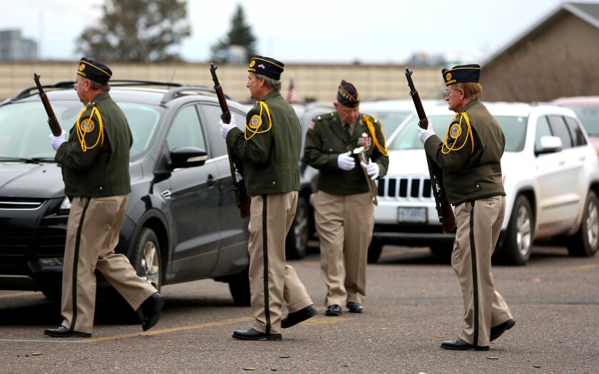 An Honor Guard marching outside in a parking lot during a Veterans Day event.