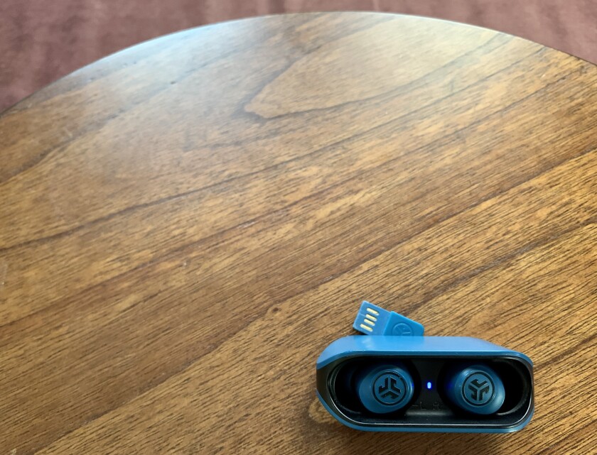 A pair of blue earbuds sits on a wooden surface.