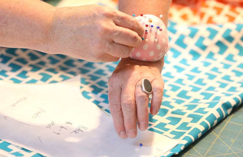Kirsten Aune grabs a pin while she attaches a pattern to fabric in her shop