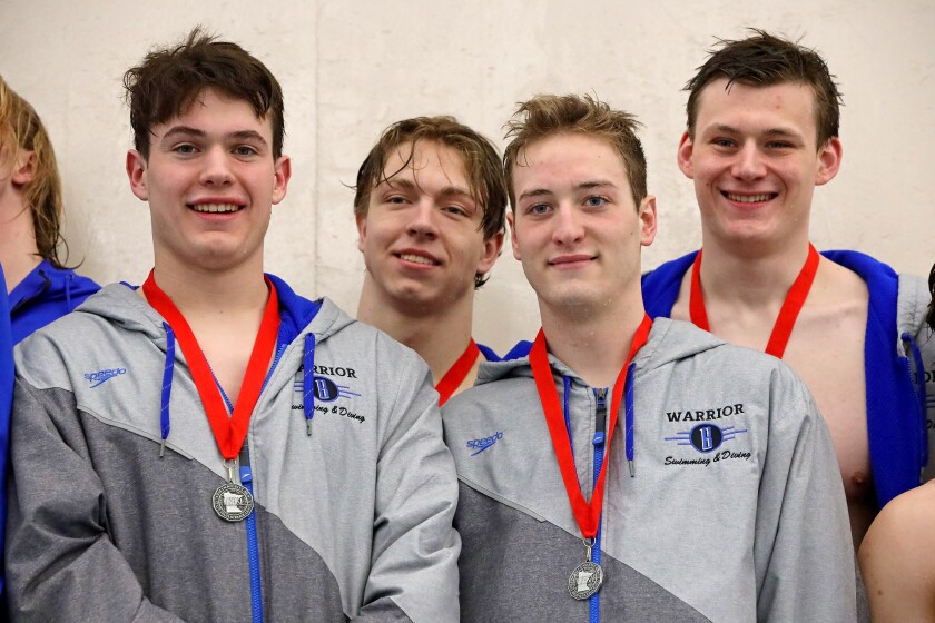 The relay team on the podium smiling with their medals.