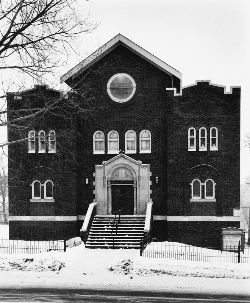 Black-and-white image of brick synagogue on snowy street.