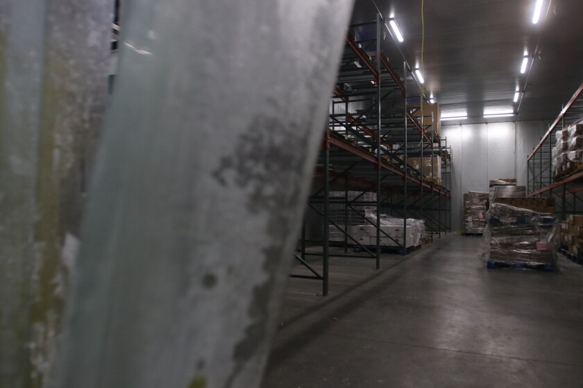 A large warehouse room has mostly empty shelves.