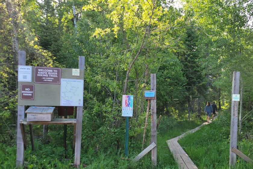 Two hikers move along the start of the Knife River Trail. A sign reads "foot travel only."