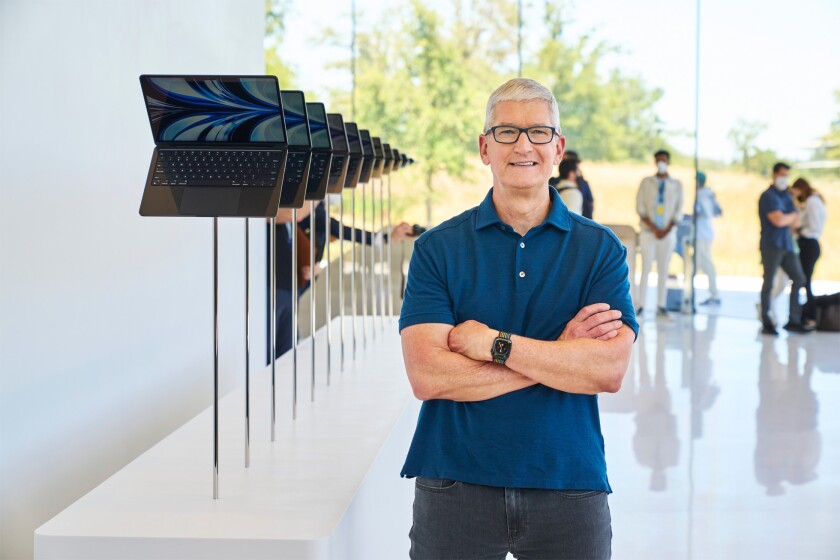 Tim Cook stands next to a row of Macbook Air laptops. 