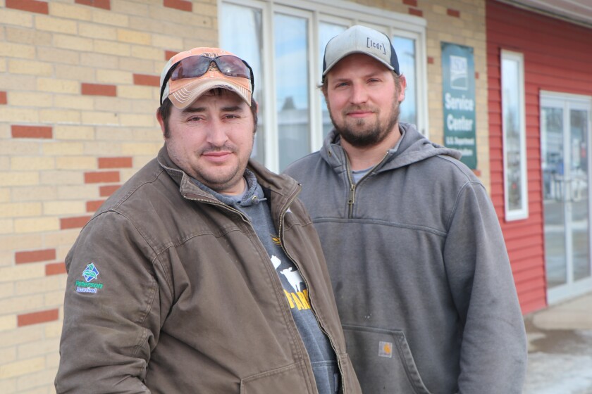 Young ranchers Ryan Wolf and Eric Giesler stand in front of the USDA's Farm Service Agency office at Ellendale, North Dakota, where they both applied for drought relief from the 2021 crop.