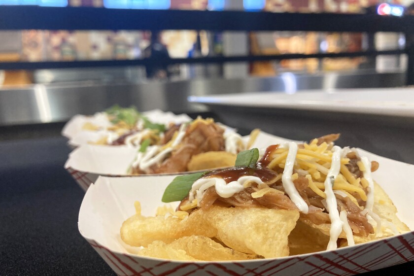 Paper trays containing barbecue chicken clipper displayed on a table inside of an arena.