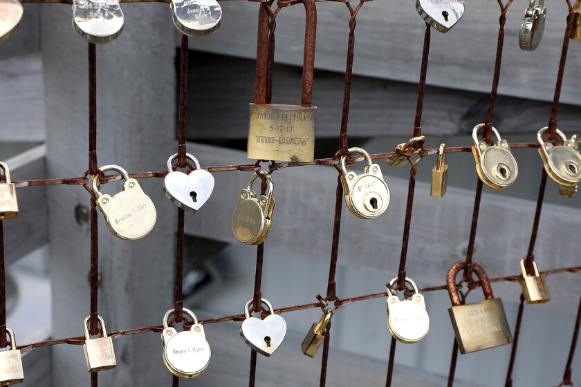 Padlocks engraved with names and dates of couples hang from a vintage bedspring