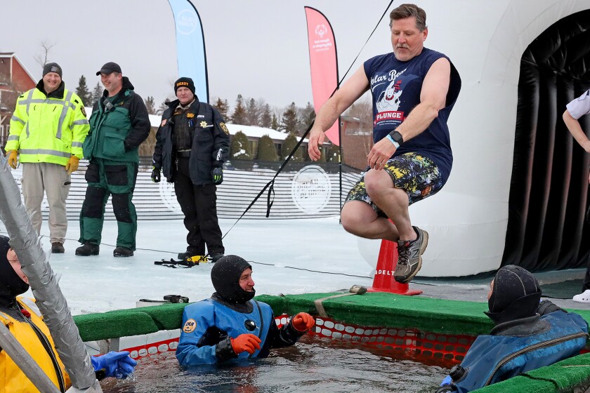 People jump into the water during the Polar Plunge event on Pelican Lake.