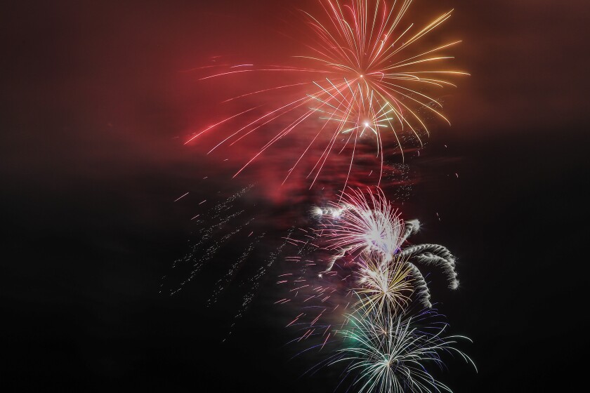 Large aerial fireworks burst in cloudy foggy night sky