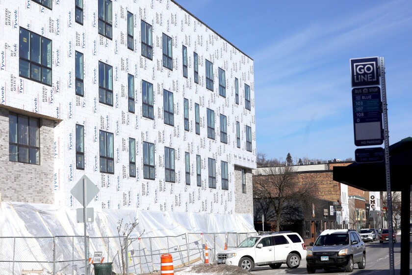 A car driving by in front of the site of a building under construction.