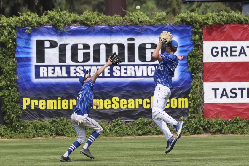High school baseball players play on outdoor field on sunny day