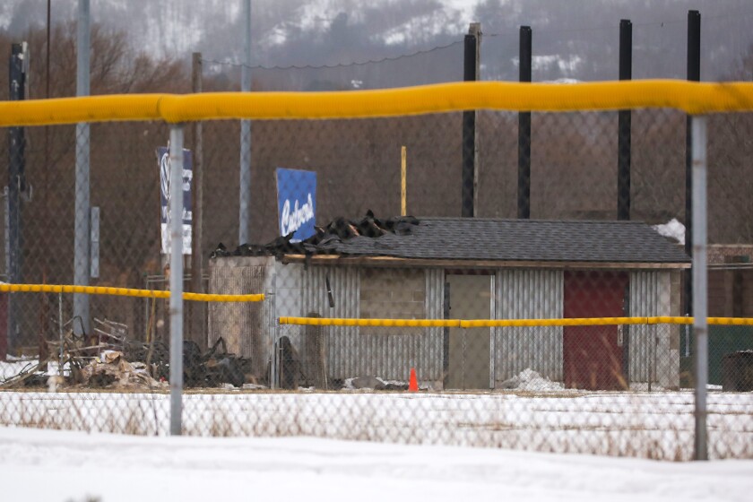 Damage to a roof of a structure at a little league baseball field in the winter with debris nearby.