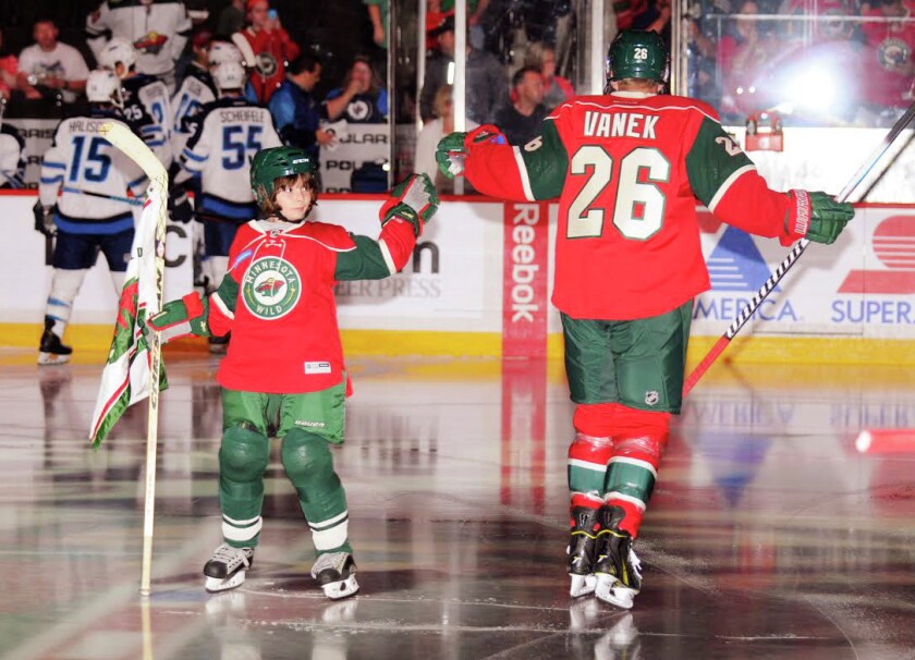 Hannah Poshek bumps fists with Minnesota Wild player Thomas Vanek.