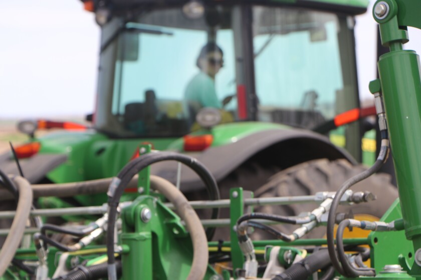 A woman plants corn with a John Deere planter.
