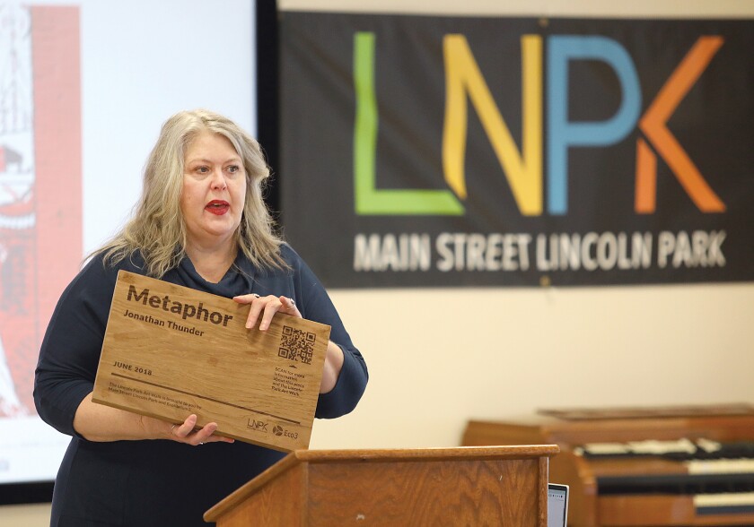 Shannon Laing, Main Street Lincoln Park Program Director, holds a plaque that will be on all murals in the Lincoln Park district