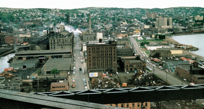 Aerial view of Duluth downtown and hillside, with bridge beams visible in foreground.
