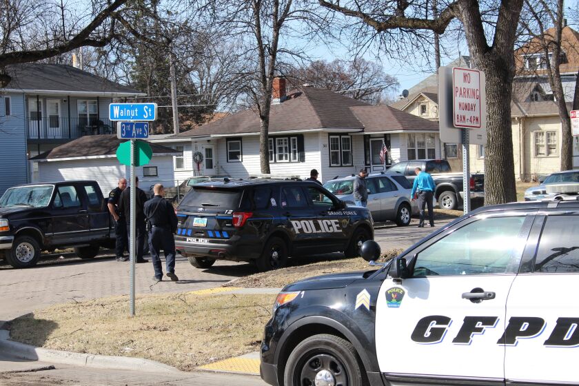 Police examine the scene of an pedestrian-vehicle collision at the corner of Walnut Street and Third Avenue South in Grand Forks Monday morning. The pedestrian was hospitalized. The dark F-150 at the intersection was also damaged.
